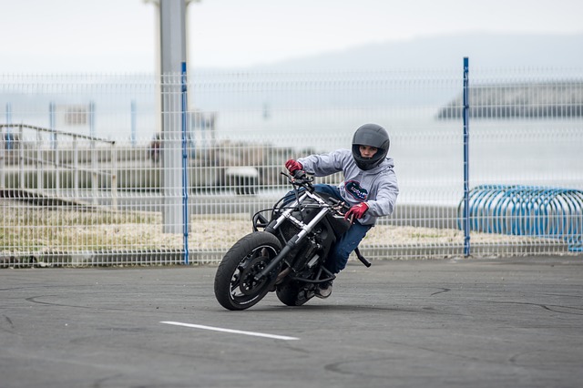 Chlapec v sivej bunde a modrých nohaviciach riadi motorku a má na hlave prilbu.jpg